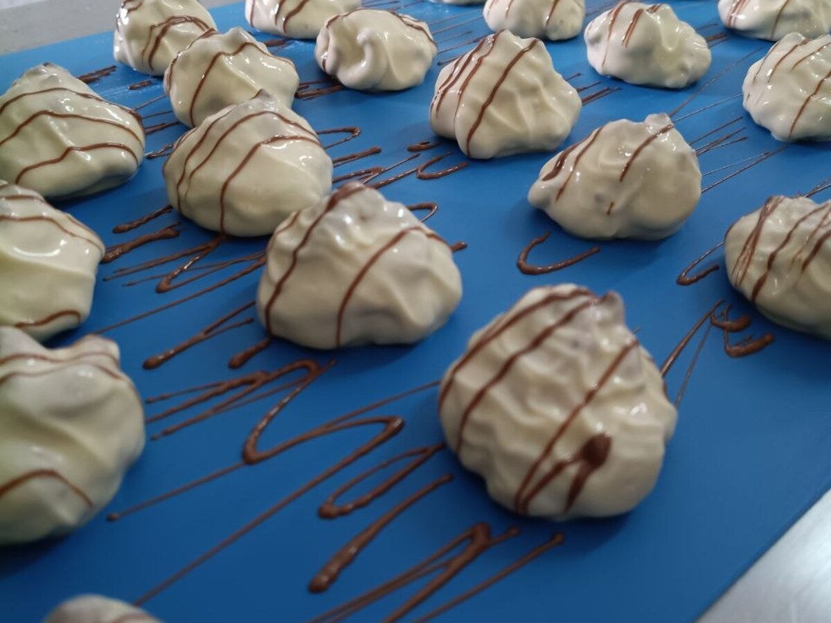 Tartuffi Bianchi just decorated with the chocolate drizzle, before the cooling tunnel