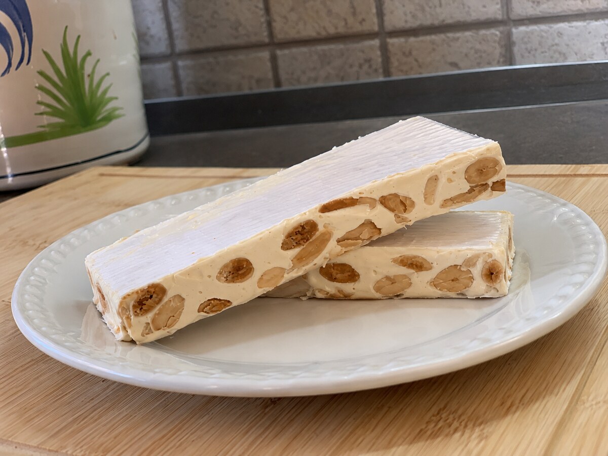 Trancetti di Torrone Bianco alle mandorle su un piatto bianco, con le mandorle in sezione